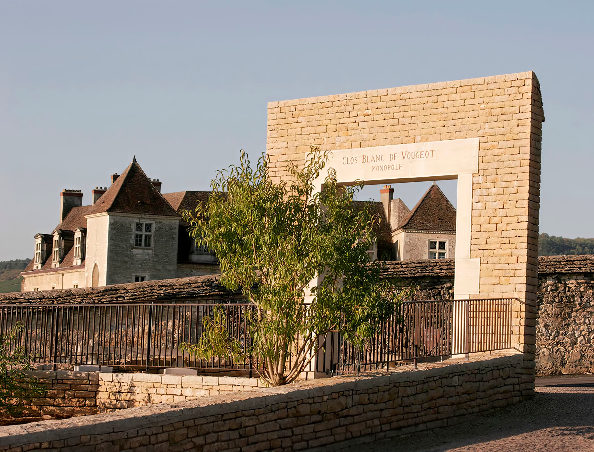 Stone gateway inscribed Clos Blanc de Vougeot Monopole, with the château beyond